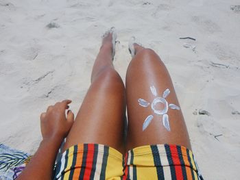 Leg of a woman on the beach, with a drawing of the sun.