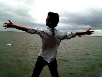 Man standing on beach against cloudy sky