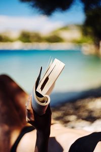 Close-up of hand holding umbrella on beach