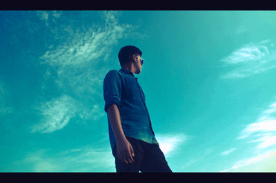 Low angle view of young man looking at blue sky