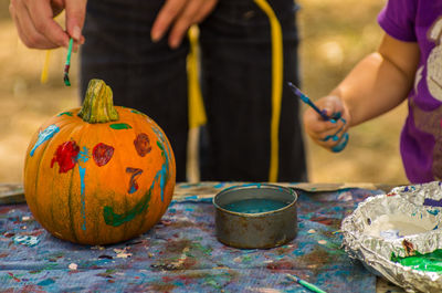 Image of hand painting pumpkin at table during halloween