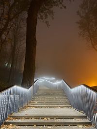 Footpath by railing against sky during sunset