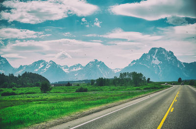 Scenic view of road by mountains against sky