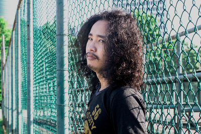 Portrait of young man by fence