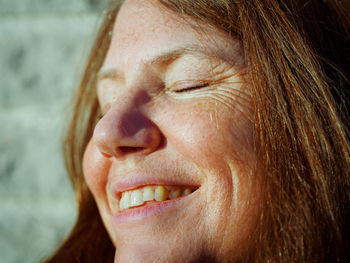 Close-up of smiling woman with closed eyes at home