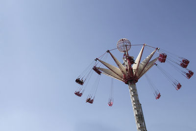 Low angle view of chain swing ride against clear blue sky