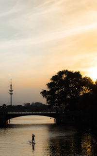 Bridge over lake with heinrich-hertz-turm in background against sky during sunset