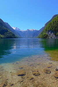 Scenic view of lake and mountains against clear blue sky