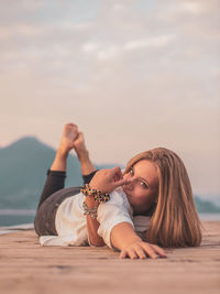 Portrait of woman lying down against sky