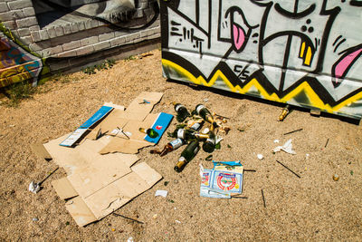 High angle view of broken liquor bottles by cardboard and graffiti