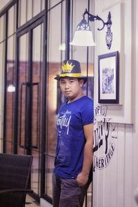 Portrait of young man standing against wall