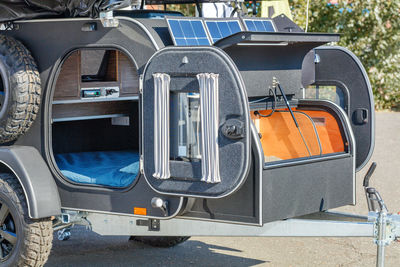 Compact road trailer mini-house for travel illuminated by summer sunbeams.