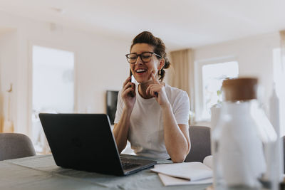 Smiling woman talking via cell phone at home