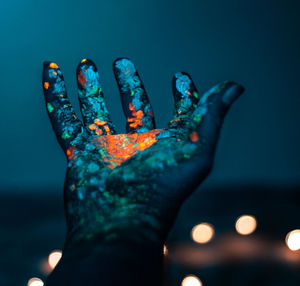 Close-up of painted hand against illuminated blue sky