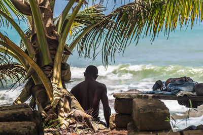 Man sitting on rock by sea