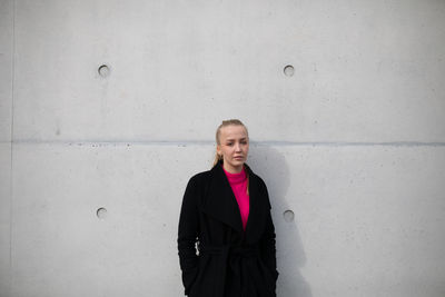 Portrait of woman standing against wall