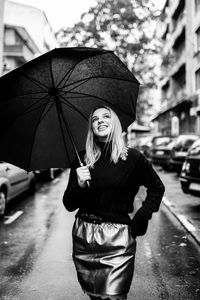 Young woman with umbrella standing in rain