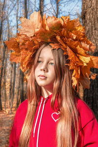 Portrait of beautiful young woman with autumn leaves