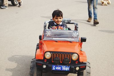 Portrait of boy sitting in toy car
