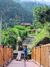 Rear view of two people walking on footpath