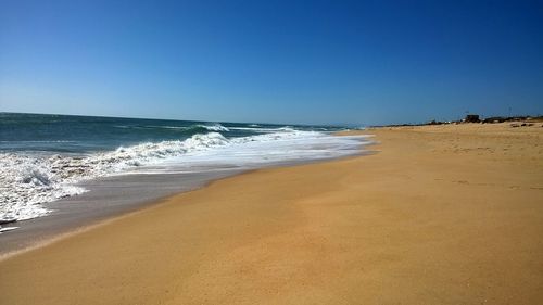 Scenic view of beach against clear blue sky