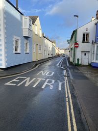 Road by buildings against sky in city