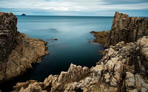 Rock formations by sea against sky