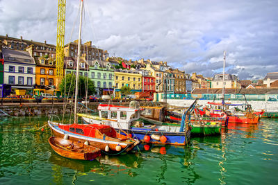 Fishing boats in sea against buildings