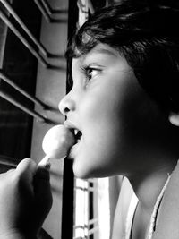 Close-up side view of girl eating lollipop at home
