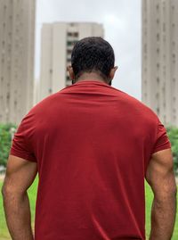 Rear view of man standing against building in city