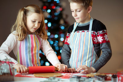 Siblings preparing food on table at home