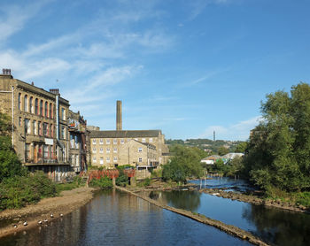 Buildings by river against sky in city