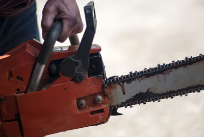 Midsection of man holding chainsaw