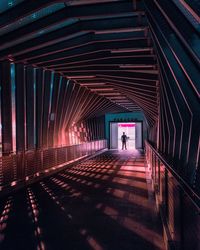 Rear view of man walking on illuminated walkway