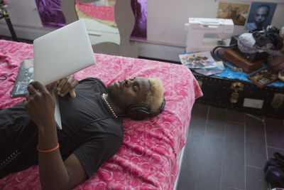 A young man lying down with a laptop in bed