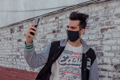 Portrait of young man with face mask in city against clear sky