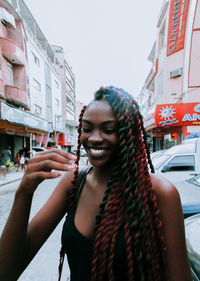 Portrait of smiling young woman standing on street in city