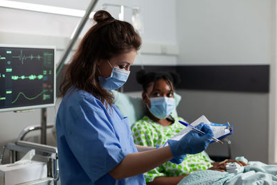 Nurse wearing mask examining patients reports