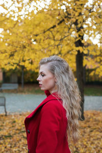 Young woman with red leaves in park during autumn