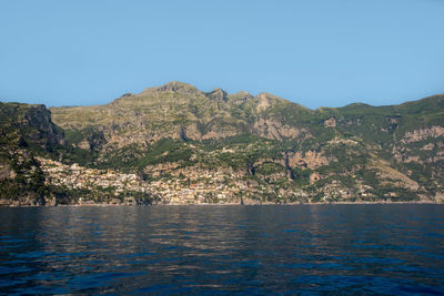 Scenic view of sea and mountains against clear blue sky