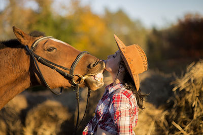 Young farmer woman playing with her horse in a sunny day inside corral ranch 