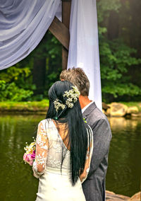 Rear view of couple standing by lake