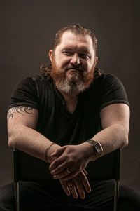 Portrait of smiling man sitting against black background