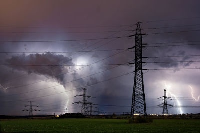 Low angle view of electricity pylon on field against sky