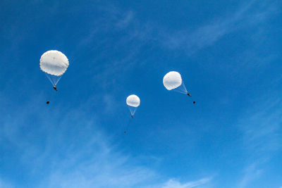 Low angle view of people on parachute against blue sky