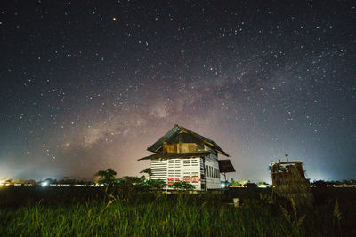 House on field against sky at night