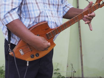 Midsection of man playing guitar