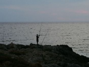 Silhouette of man fishing at sunset