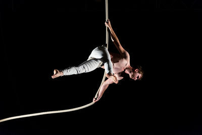 Young man doing gymnastics against black background