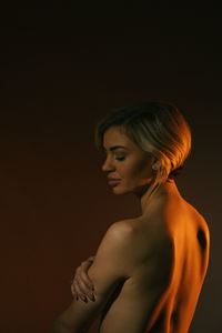 Side view of young woman against black background